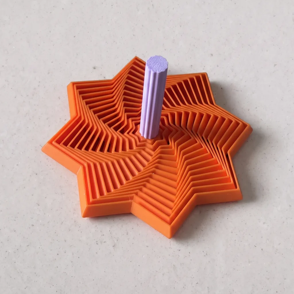 Estrella espiral impresa en 3D en naranja con eje lila, plegada