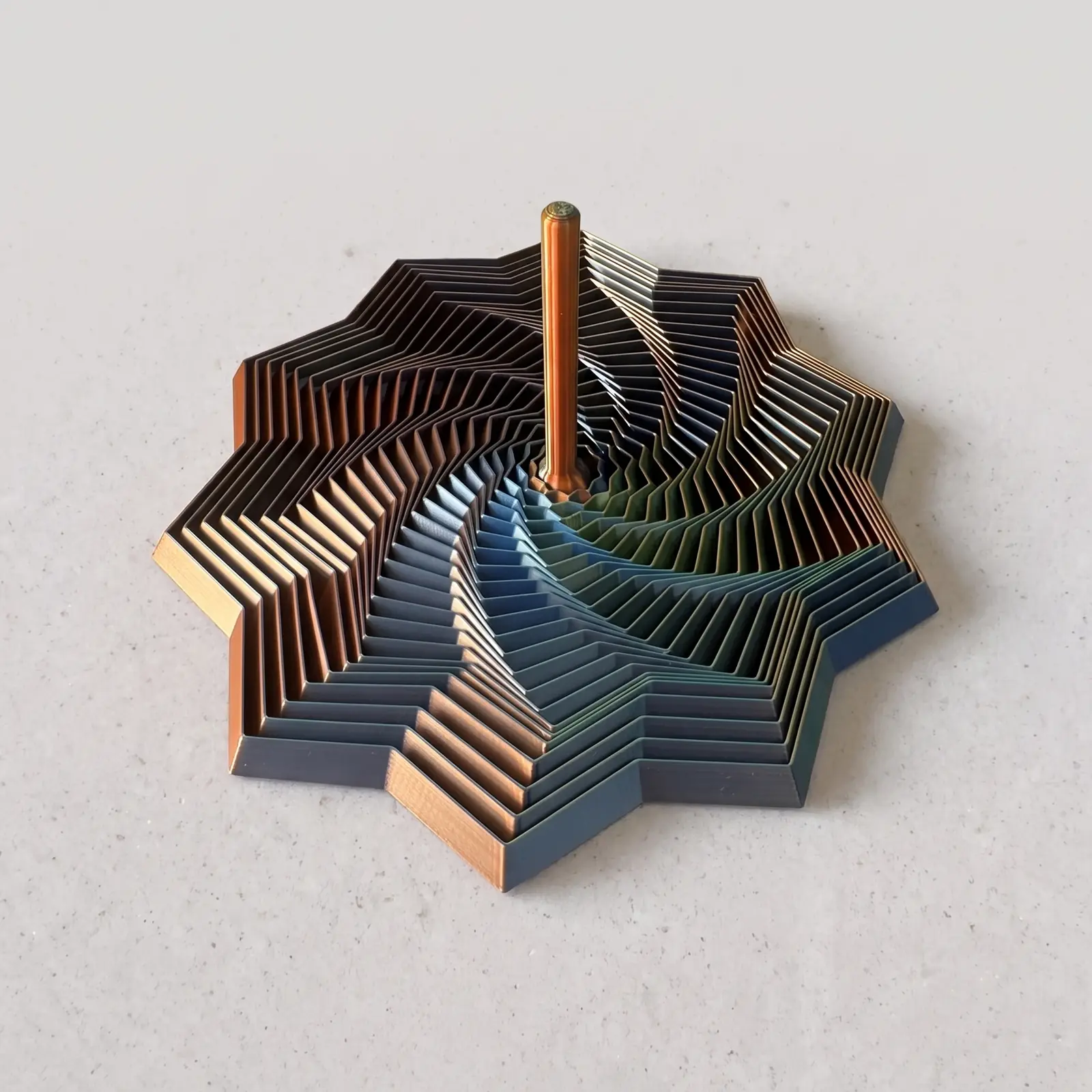 Estrella espiral grande impresa en 3D en filamento Silk azul, verde y naranja, con eje central