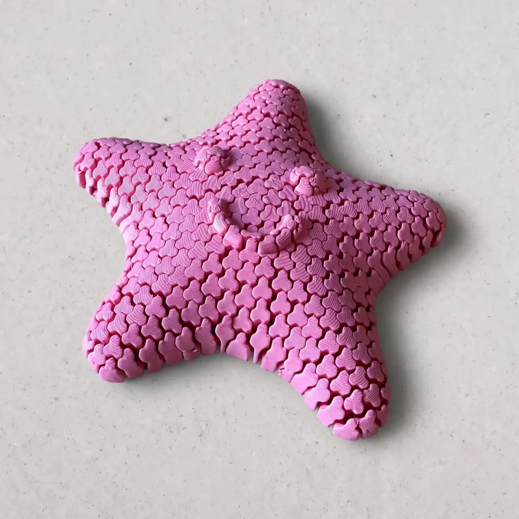 Estrella de mar articulada impresa en 3D en rosa, con carita sonriente, vista en ángulo