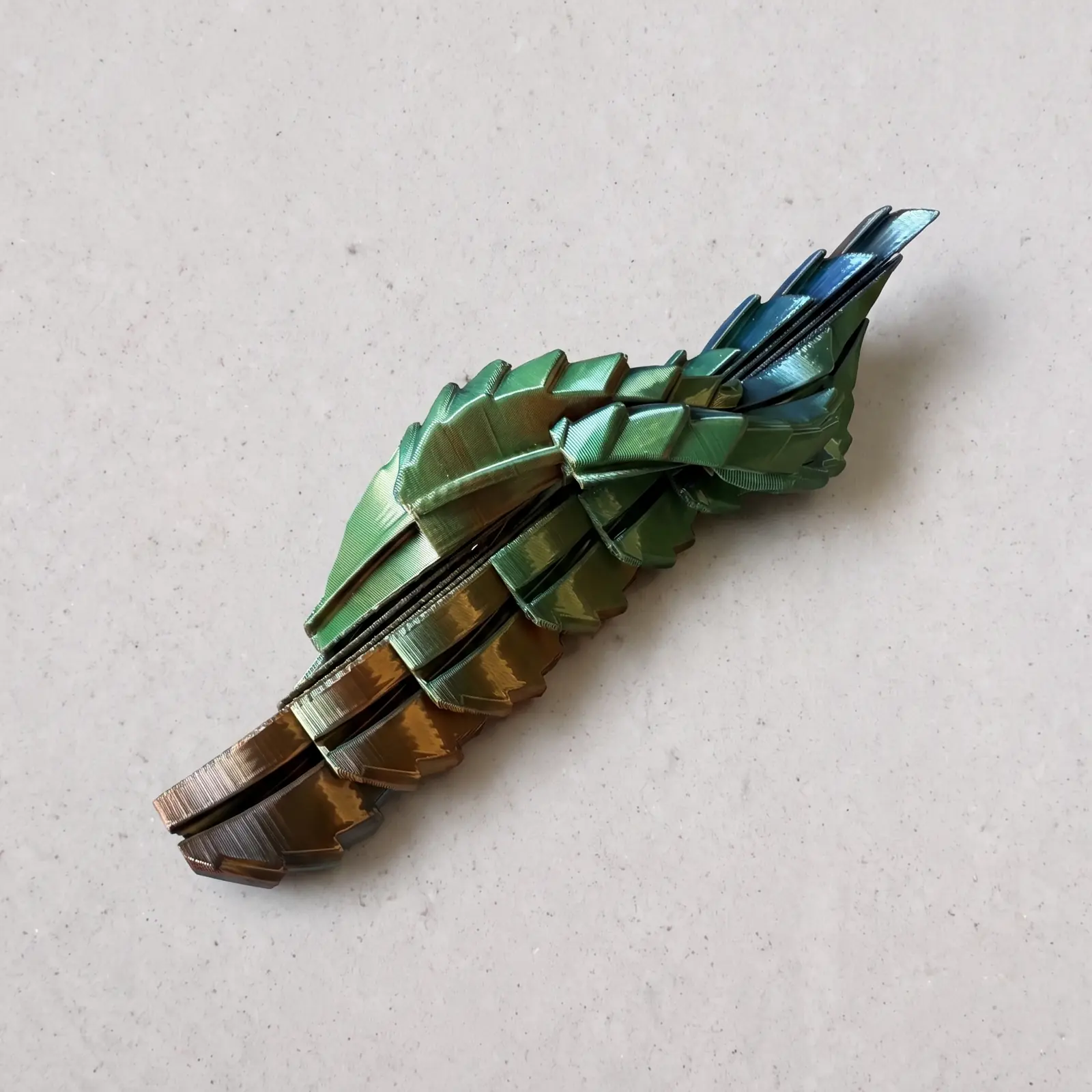 Dragón articulado impreso en 3D en filamento Silk verde, azul y cobre, desplegado