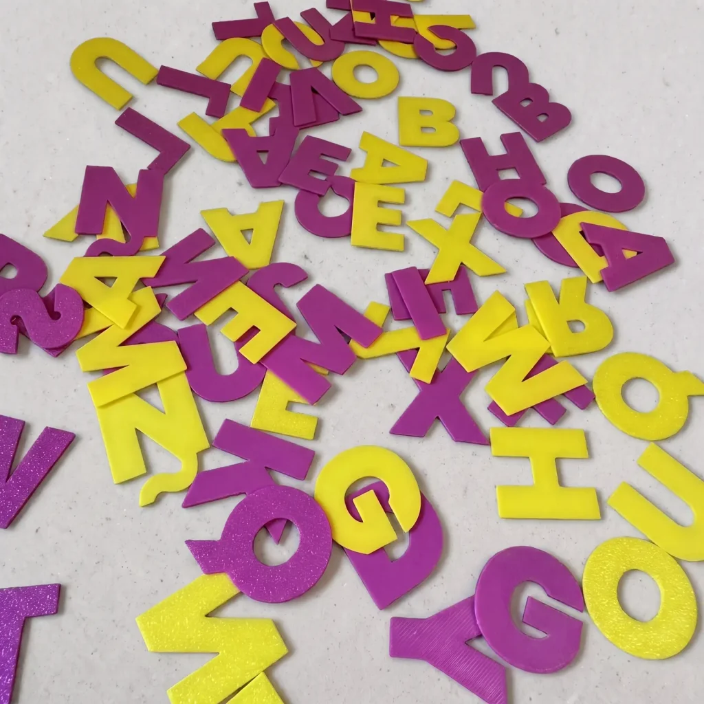 Letras sueltas impresas en 3D en amarillo y violeta sobre la mesa