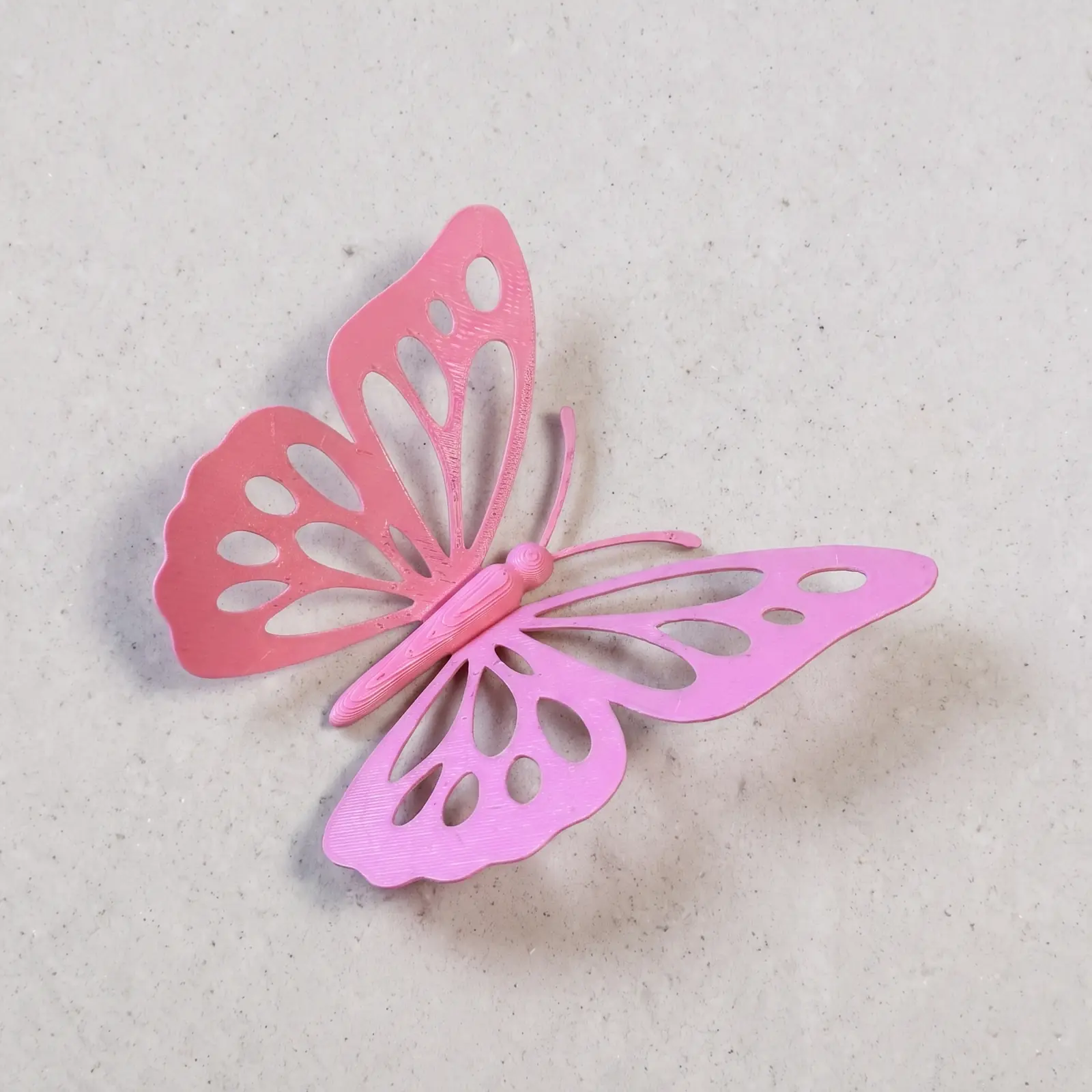 Mariposa decorativa impresa en 3D en rosa, con alas caladas