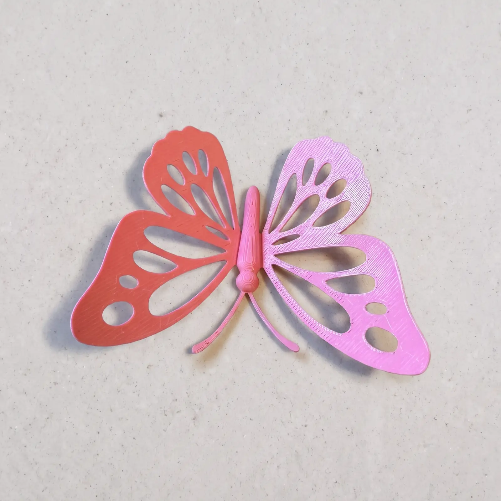 Mariposa decorativa rosa vista en ángulo, con las nervaduras caladas de las alas