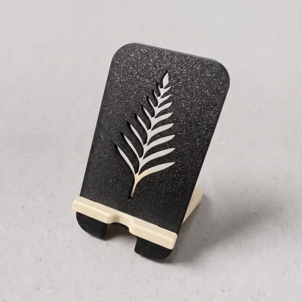 Porta celular impreso en 3D, diseño Helecho: espalda negra con una hoja de helecho calada y soporte beige