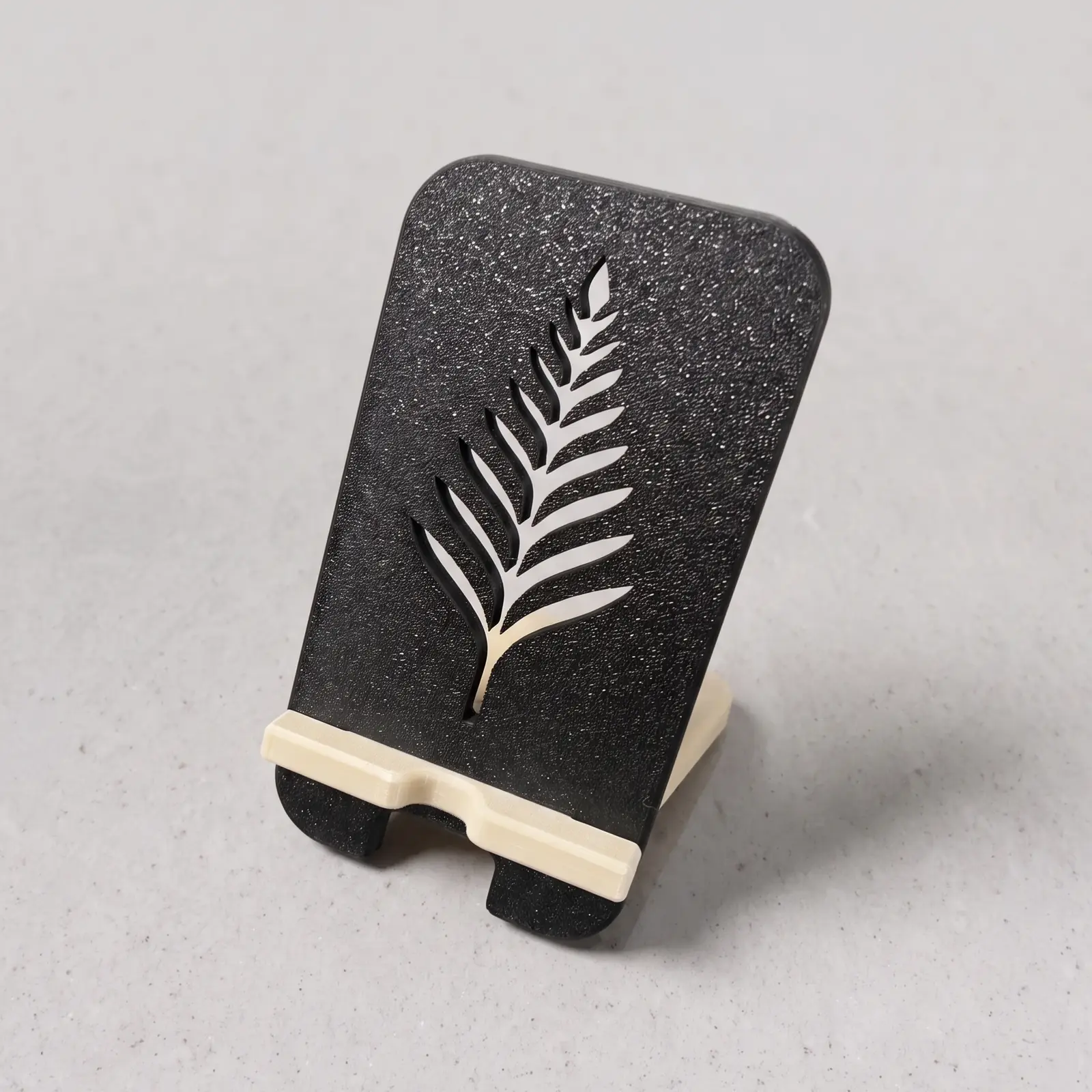 Porta celular impreso en 3D, diseño Helecho: espalda negra con una hoja de helecho calada y soporte beige