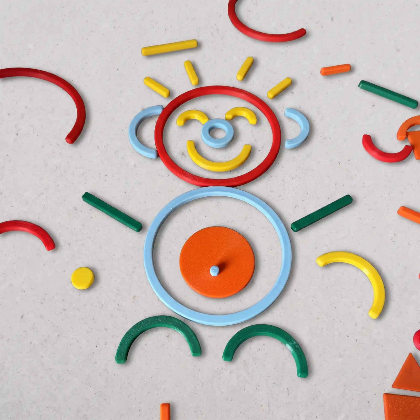Piezas de colores impresas en 3D formando una cara sonriente con rayos de sol