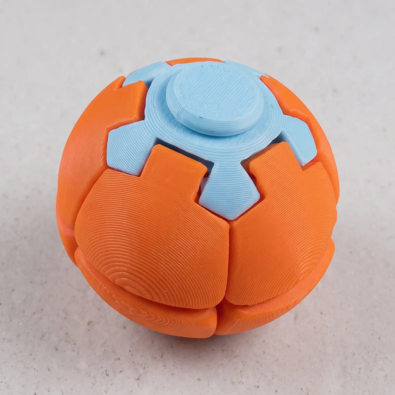 Trompo esfera impreso en 3D en naranja y celeste, cerrado como esfera